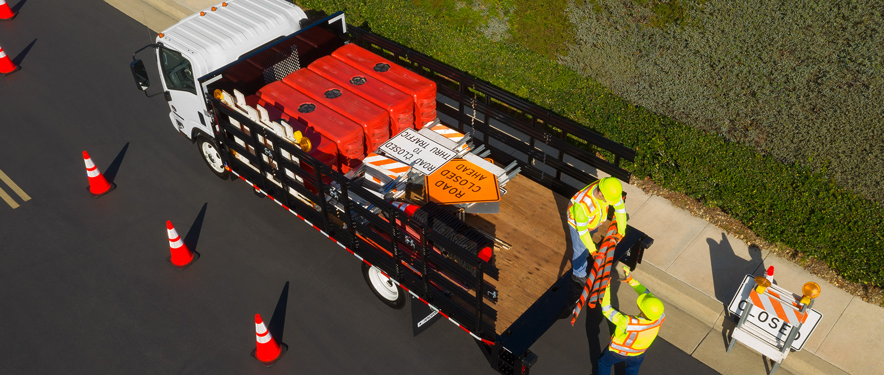 Employés de travaux publics utilisant le Prostake avec plate-forme/benne basculante pour installer des panneaux routiers pour une construction